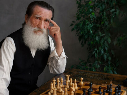 An elderly man deeply focused on a solo chess game, strategizing his next move