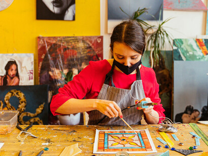 Artist in a studio painting on a wooden table, hands actively working with materia