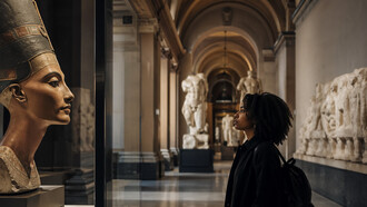 Uma visitante observa o busto de Nefertiti em uma galeria europeia: símbolo de beleza e poder, a peça também representa o debate sobre a permanência de patrimônios retirados de seus contextos originais
