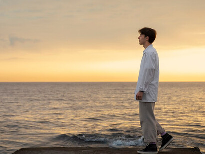 A contemplative man stands at the seaside, reflecting on stillness and mindfulness while enjoying the quiet moments offered by nature