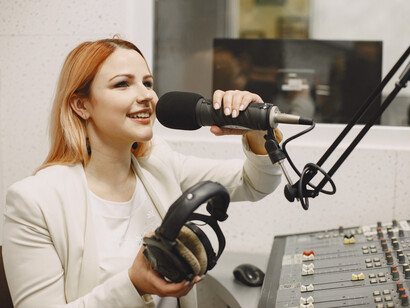 A woman recording on a studio microphone, sitting at the control room. 