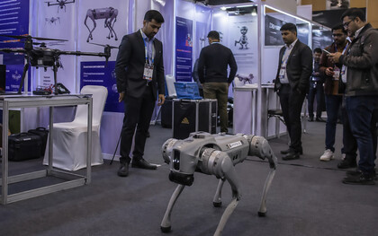 A robotics demonstration at a crowded technology exhibition, where a quadruped robot and surrounding displays highlight the fine line between innovation, presentation, and perception in modern AI showcases