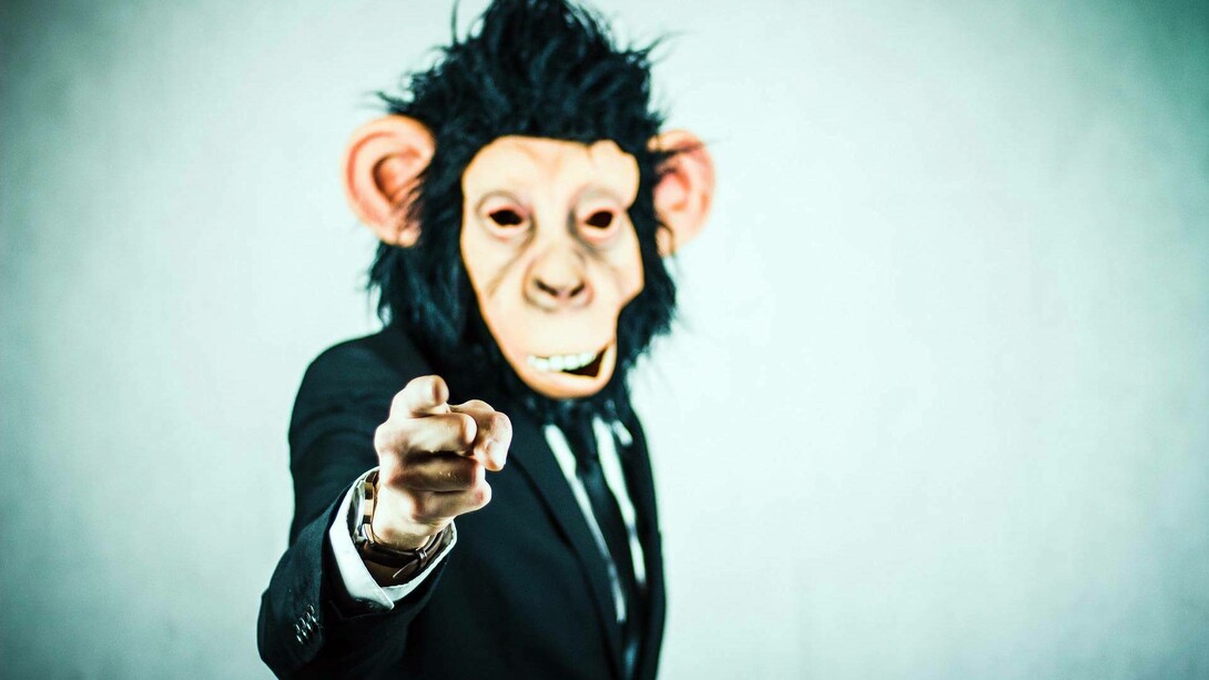 Human being posing as a monkey while wearing a suit
