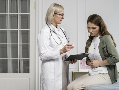 A woman sitting through a medical consultation with abdominal pain, representing the difficulties many women face before receiving answers