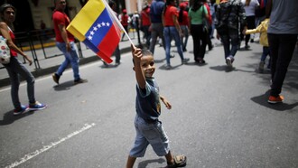 Un niño con la bandera venezolana por las calles de Caracas