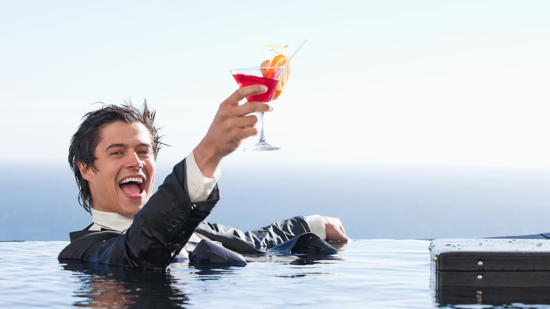 Un ejecutivo bañándose vestido y disfrutando de un cóctel