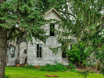 A faded home surrounded by nature, representing the stories that remain long after the years have passed