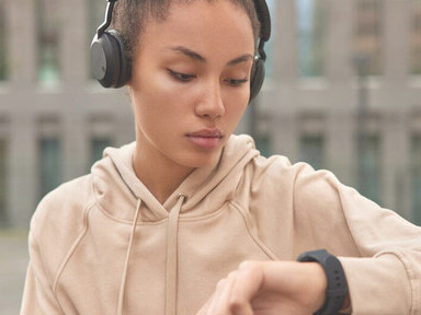 A fitness model, wearing a beige sweatshirt, checks workout results on her smartwatch after exercising outdoors, showcasing the integration of wearable devices and smart technology in fitness, emblematic of technological disruptions