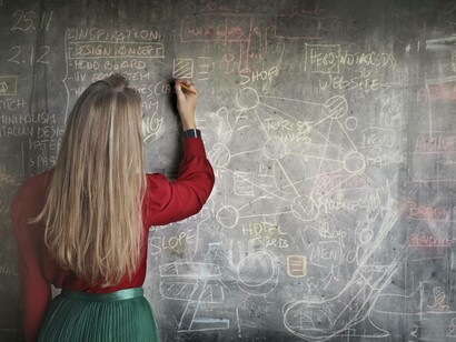 An educator writing on the blackboard with the thought that her job might be taken by an AI robot