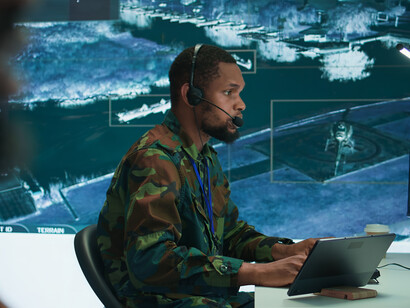A cybersecurity team works in an advanced military command center, analyzing data and defending against cyber threats