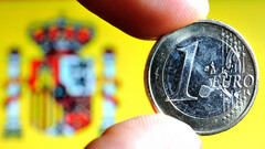 Moneda de un euro con la bandera española al fondo