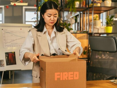 An office employee gathering personal items after losing their role, reflecting the anxiety tied to technological disruption