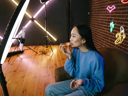 A content creator broadcasts live from a vibrant neon-lit space, connecting with viewers through technology and engaging online entertainment