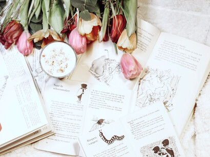 Tulips and a drink sit among several open books to read
