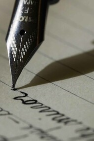 A sleek fountain pen glides across the black lined paper, leaving behind elegant strokes of ink