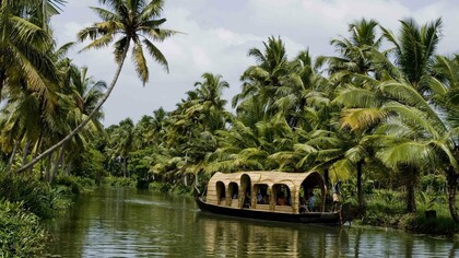 A houseboat with tourists, snaking its way through the backwaters of Kumarakom