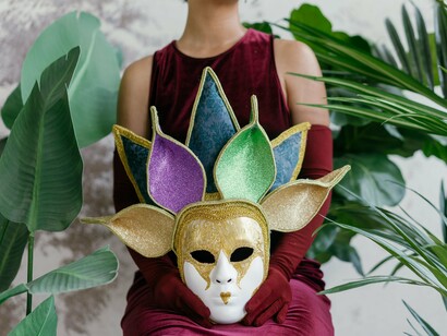 A person holding an elaborate mask, reflecting the hidden cost of performing success instead of living honestly