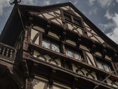 A picturesque scene featuring a charming building adorned with a balcony, alongside the captivating Castelul Pelișor, all set against the scenic backdrop of Sinaia, Romania