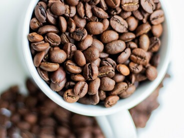 Freshly roasted coffee beans overflowing from a ceramic cup, representing coffee at the heart of Japan's café culture