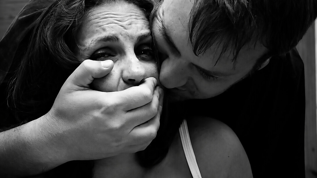 A violent scene depicting a man restraining a woman and covering her mouth during a physical assault