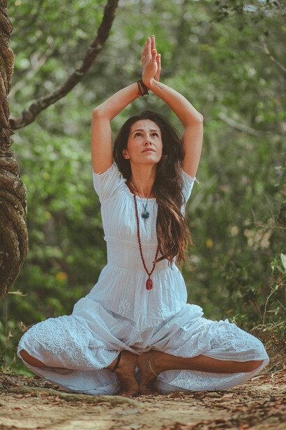 A woman crouching on the ground with her arms raised toward the sky in a gesture of release and reflection