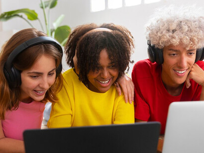 A medium shot of friends watching videos on a computer, highlighting the influence of digital platforms and social media on global communication