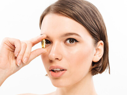 Portrait of a vibrant woman with dark hair, happily holding a multivitamin capsule as part of her daily wellness routine