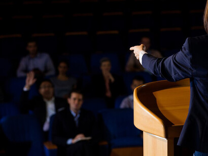 A female leader speaking passionately, highlighting themes of democracy, civic voice, and fair representation