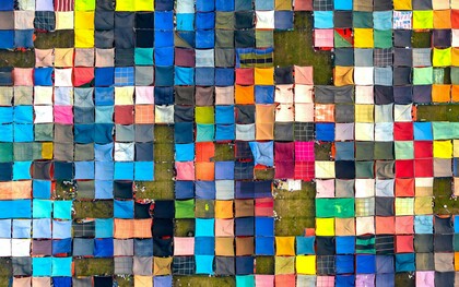 Vista aérea de tecidos coloridos secando ao ar livre em Dhaka, Bangladesh, mostrando práticas têxteis culturais. As diferentes cores e padrões criam uma composição visual que destaca a diversidade presente no universo têxtil. Durante séculos, a produção dessas tonalidades envolveu processos químicos e naturais que marcaram profundamente a relação entre moda, saúde e meio ambiente. Hoje, compreender a origem dos corantes e os impactos da indústria tornou-se parte essencial de um consumo mais consciente e sustentável