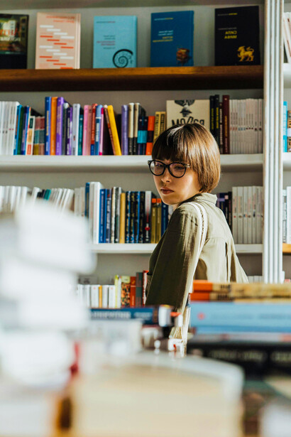 Estudiante recorriendo las estanterías y mesas de una biblioteca