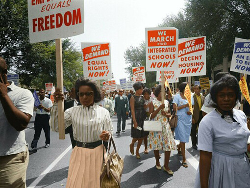 Demonstrators march down the street holding signs demanding voting rights and equal civil rights at the 1963 March on Washington, US
