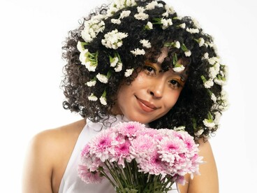 A woman smiling softly holding a bouquet of flowers, symbolising the freedom that comes from embracing ourselves as imperfect humans