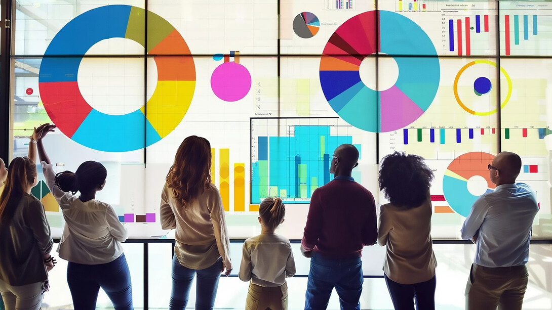 A diverse group of people, including children, engaging with vibrant data visualization charts displayed on a sleek glass wall