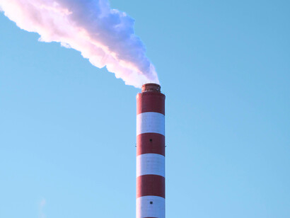 Cheminées industrielles et fumées de CO₂ symbolisent une économie toujours dépendante des énergies fossiles, au cœur des déséquilibres climatiques actuels