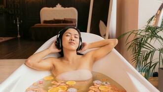 Mulher relaxa na banheira enquanto ouve música. Em um mundo onde a pressão cotidiana e as tensões emocionais se tornaram comuns, a música surge como uma aliada poderosa na busca por bem-estar emocional