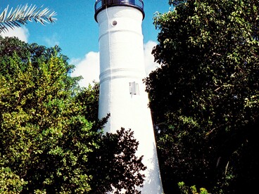The Key West Lighthouse above the treetops in Key West, Florida, symbolizing the spirit of a destination where history and literature meet