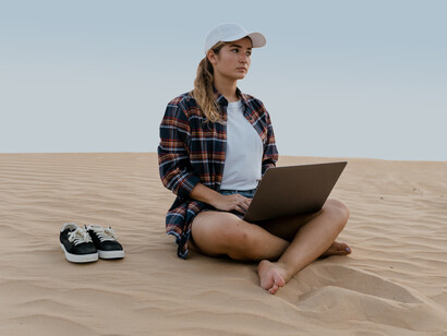 Nômade digital trabalha sentada no deserto