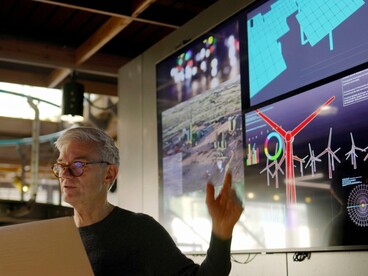 An expert attends a renewable energy seminar with information displayed on a large screen