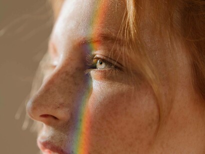A woman with a rainbow shining brightly on the left side of her face