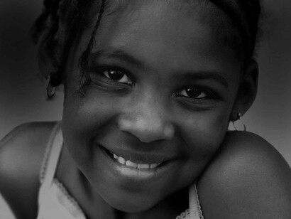 A young girl smiling with her eyes although she is tight-lipped and cautious about who she's offering that smile