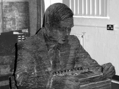 Stephen Kettle (1966), escultor. Alan Turing sentado frente a una máquina de cifrado ENIGMA. Bletchley, 2009, Milton Keynes, Buckinghamshire, Inglaterra