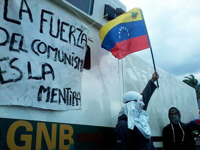 Masked protester holding a Venezuelan flag during a public demonstration in Venezuela
