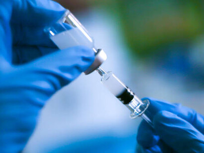 A medical professional in a glove holds an ampoule of vaccine and a syringe, illustrating the importance of vaccinations in healthcare and disease prevention