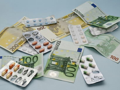 Medicine and money stacked together on a table, highlighting the financial aspect of the healthcare industry