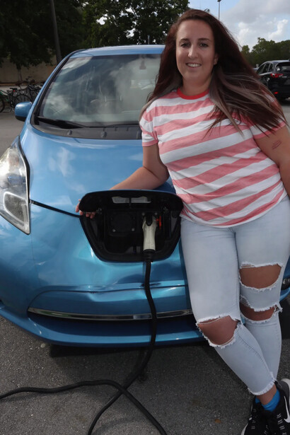 A happy female EV driver waits for the charging to be done