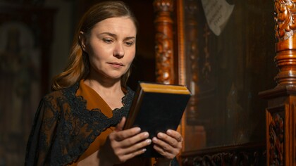A reader holding an ancient religious manuscript, representing the preservation of Katharevousa through religious practice