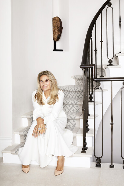 Katherine Pooley is sitting on bespoke limestone steps with a bronze staircase railing she designed for this six-floor private home next to Kensington Palace in London