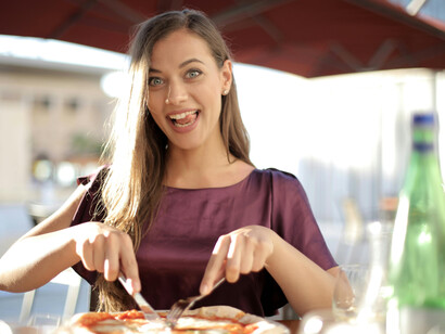 Woman slicing pizza during a long lunch, embracing slow living and mindful eating
