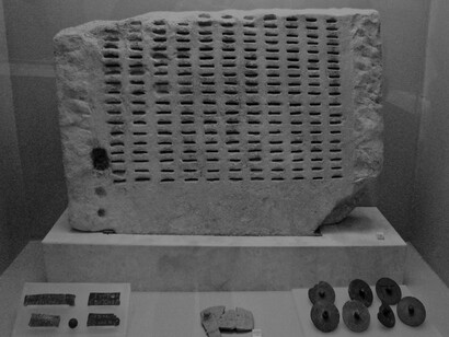 El kleroterion era un bloque de piedra rectangular con ranuras ordenadas en varias filas verticales identificadas por letras inscritas en la parte superior