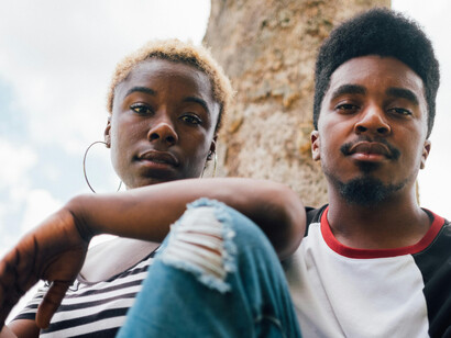 A young black man and woman looking at the camera